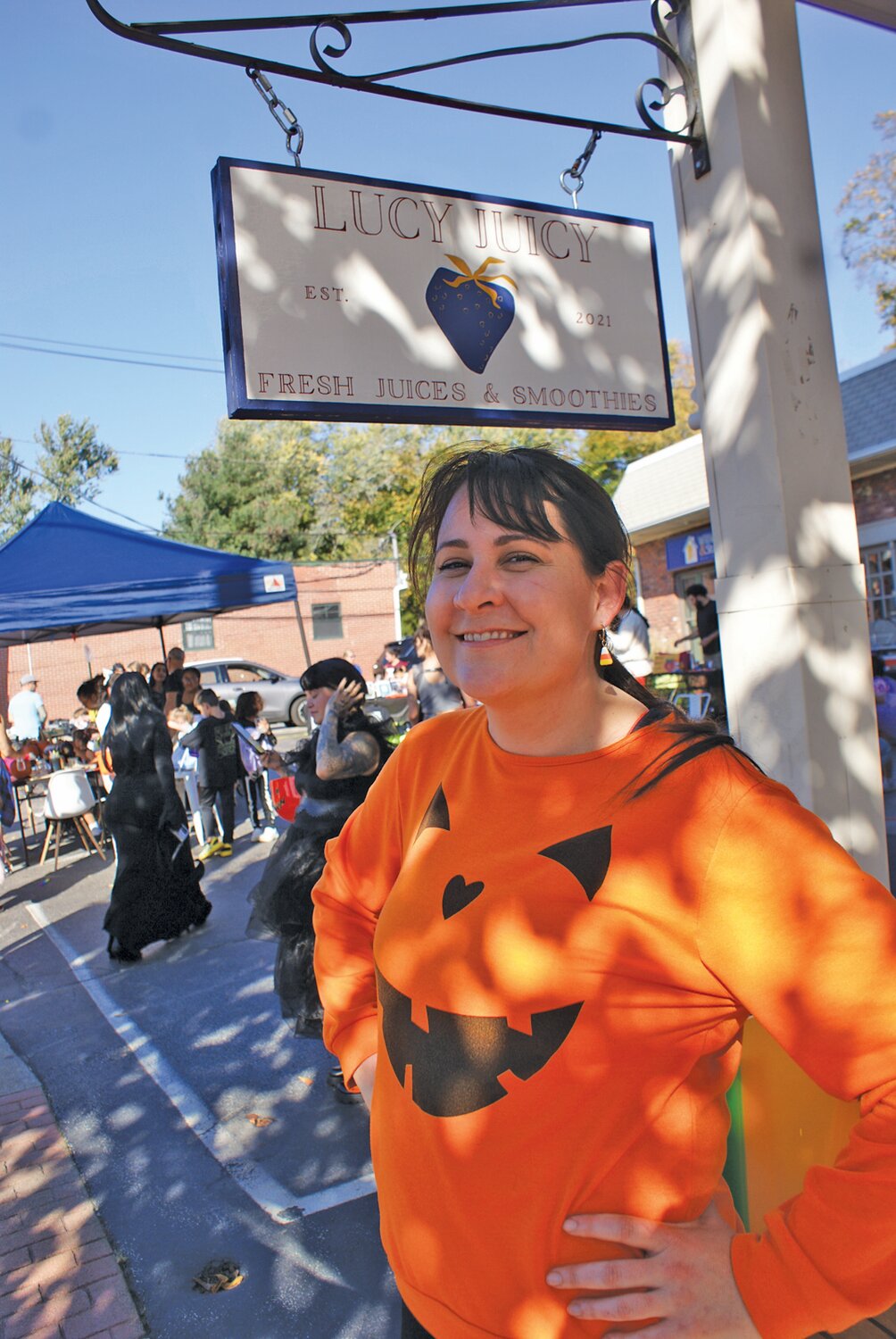 NO TRICKS JUST TREATS: Lucy Juicy owner Shawna Gierhart joins in with other business owners on Broad Street by handing out Halloween treats to excited children dressed up for the parade.